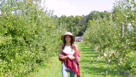 woman walks towards the camera through an orchard