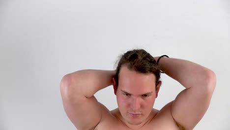 Young-white-man-with-blond-hair-without-t-shirt-showing-how-he-combs-his-hair-without-a-mask-in-closeup-with-white-background