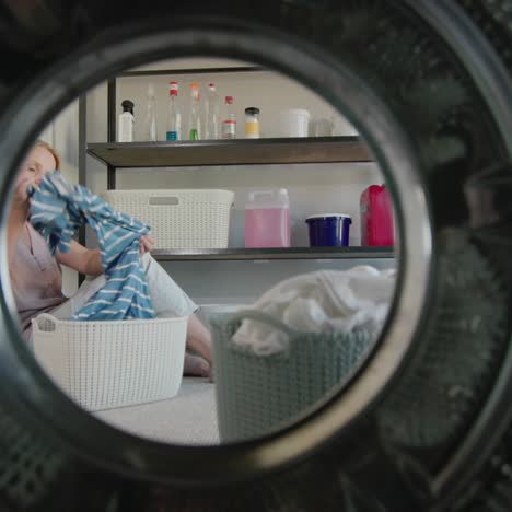 a tired woman throws clothes into the washing machine