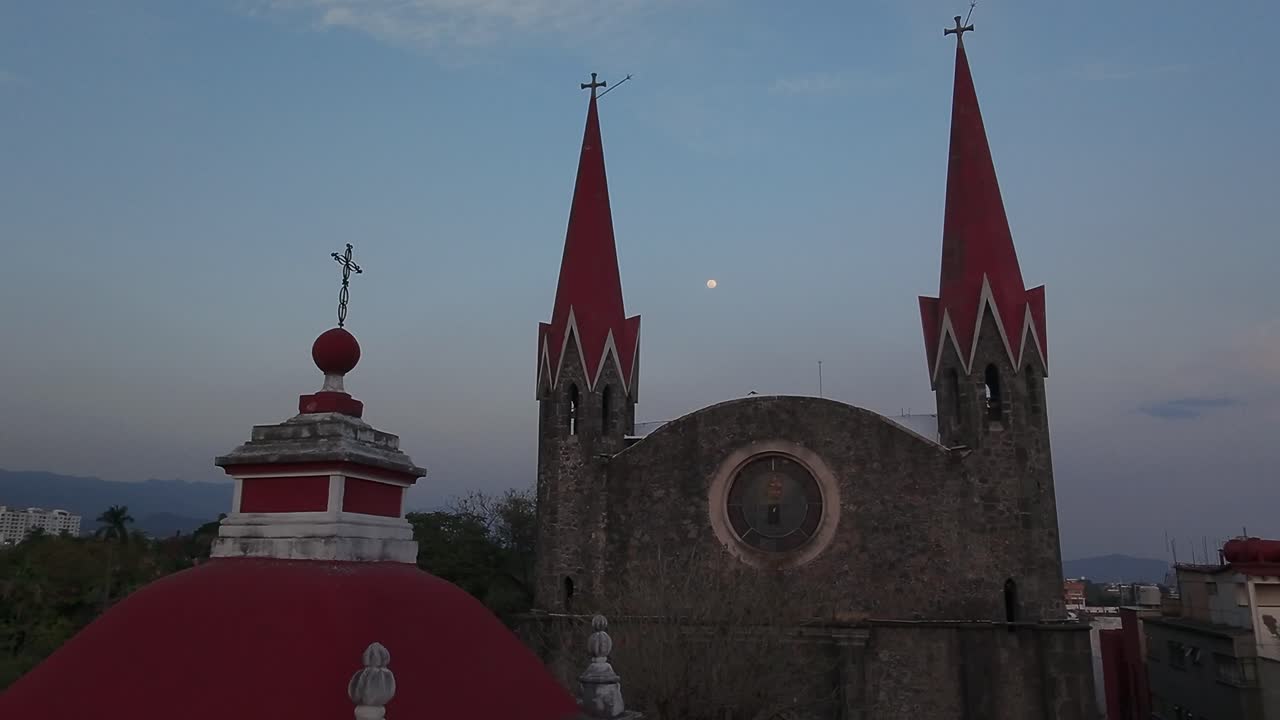Old church towers at dusk with red spires and moon in Cuernavaca, Morelos, Mexico