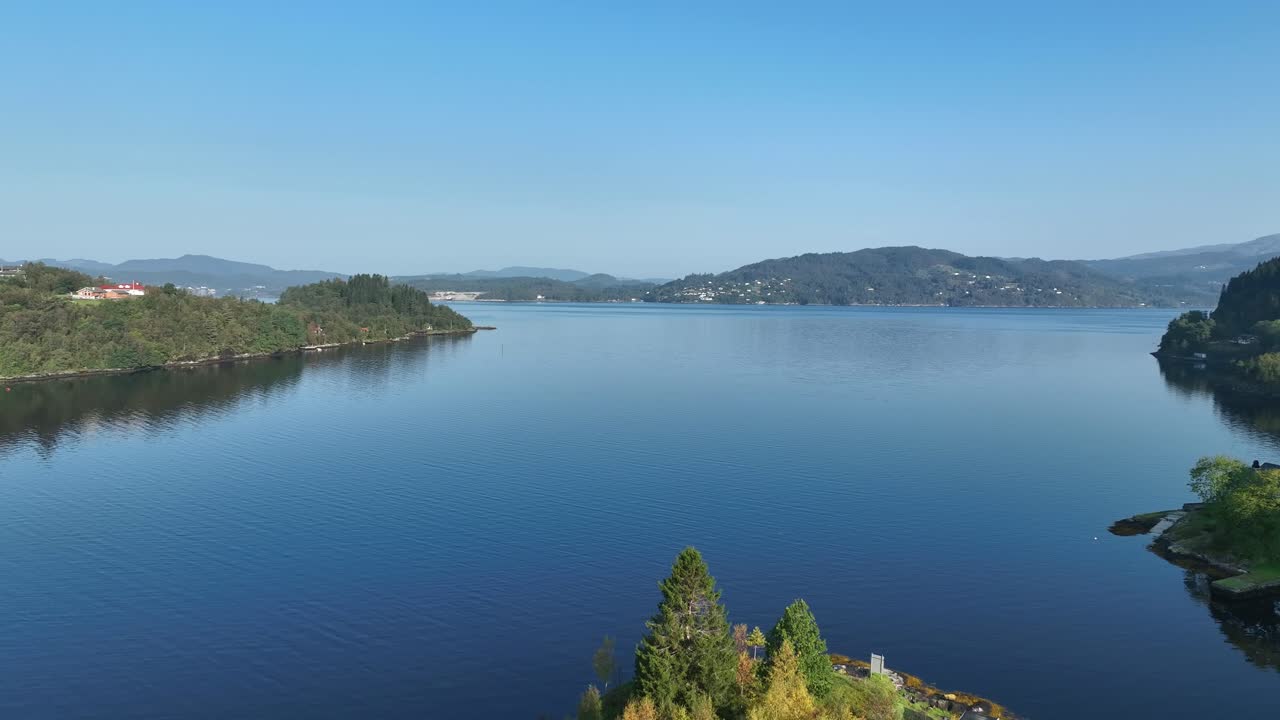 aérea hacia adelante sobre el tranquilo osterfjorden en noruega con cielos soleados y montañas