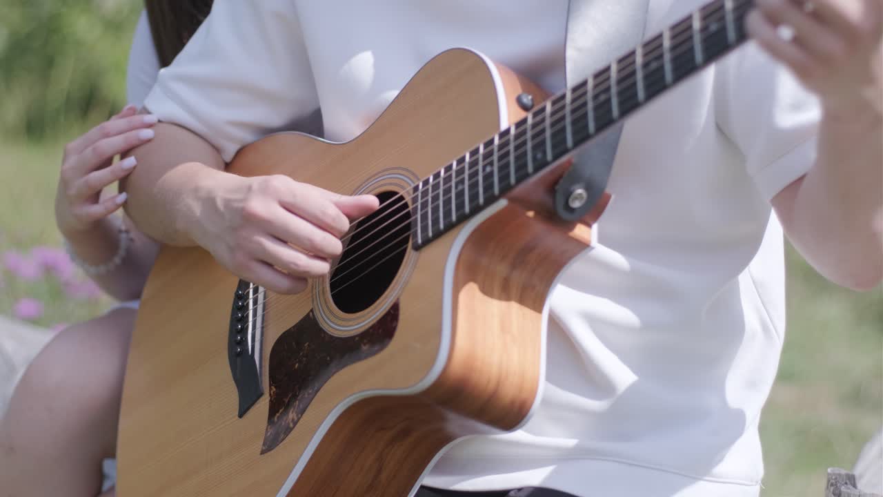 A couple playing guitar together outdoors