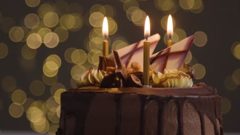 Studio-Shot-Of-Decorated-Chocolate-Birthday-Celebration-Cake-With-Lit-Candles-Against-Bokeh-Background-Lighting-1