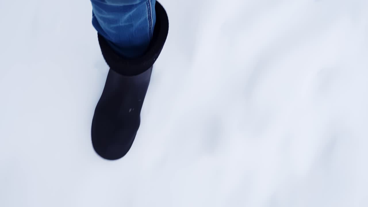 Soğuk bir kış yolunda yürüyen birinin ayak izleri bırakan botlarının taze karda yürümesinin yakın plan POV görüntüsü