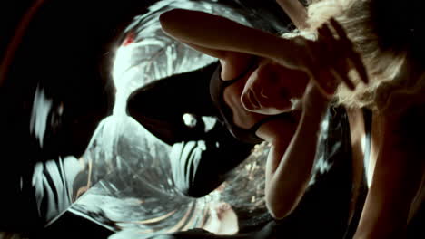 woman sitting in mirrored room with swirling abstract reflections