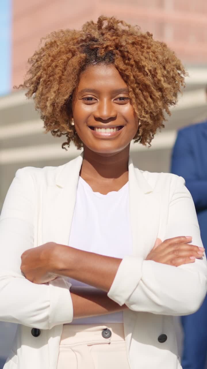 African businesswoman crossing arms and smiling outdoors