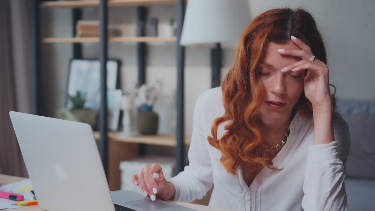 Young caucasian woman looks in laptop and gets upset about problems in business