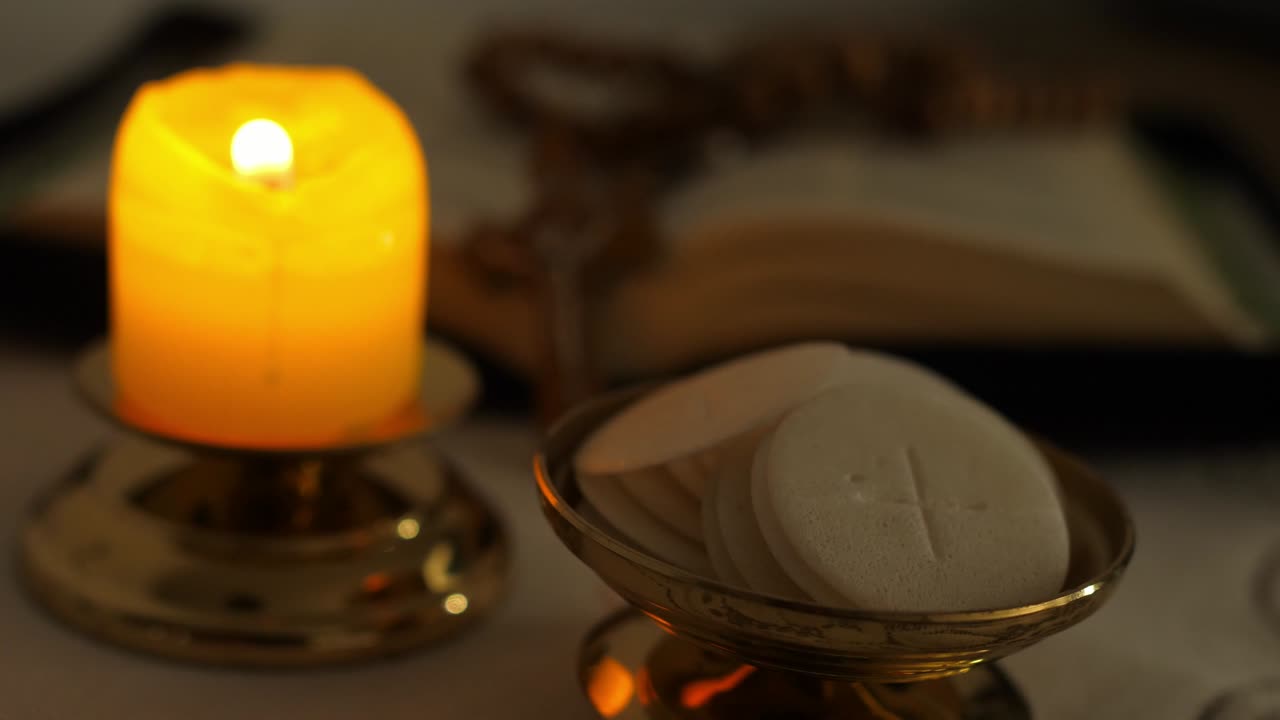 las hostias de la comunión en el crepúsculo iluminadas por la luz de un rosario de vela encendida