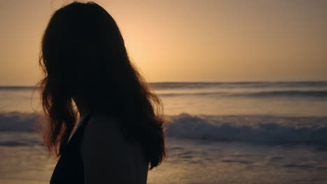 girl walking by the sea at golden hour looking at the sunset medium shot