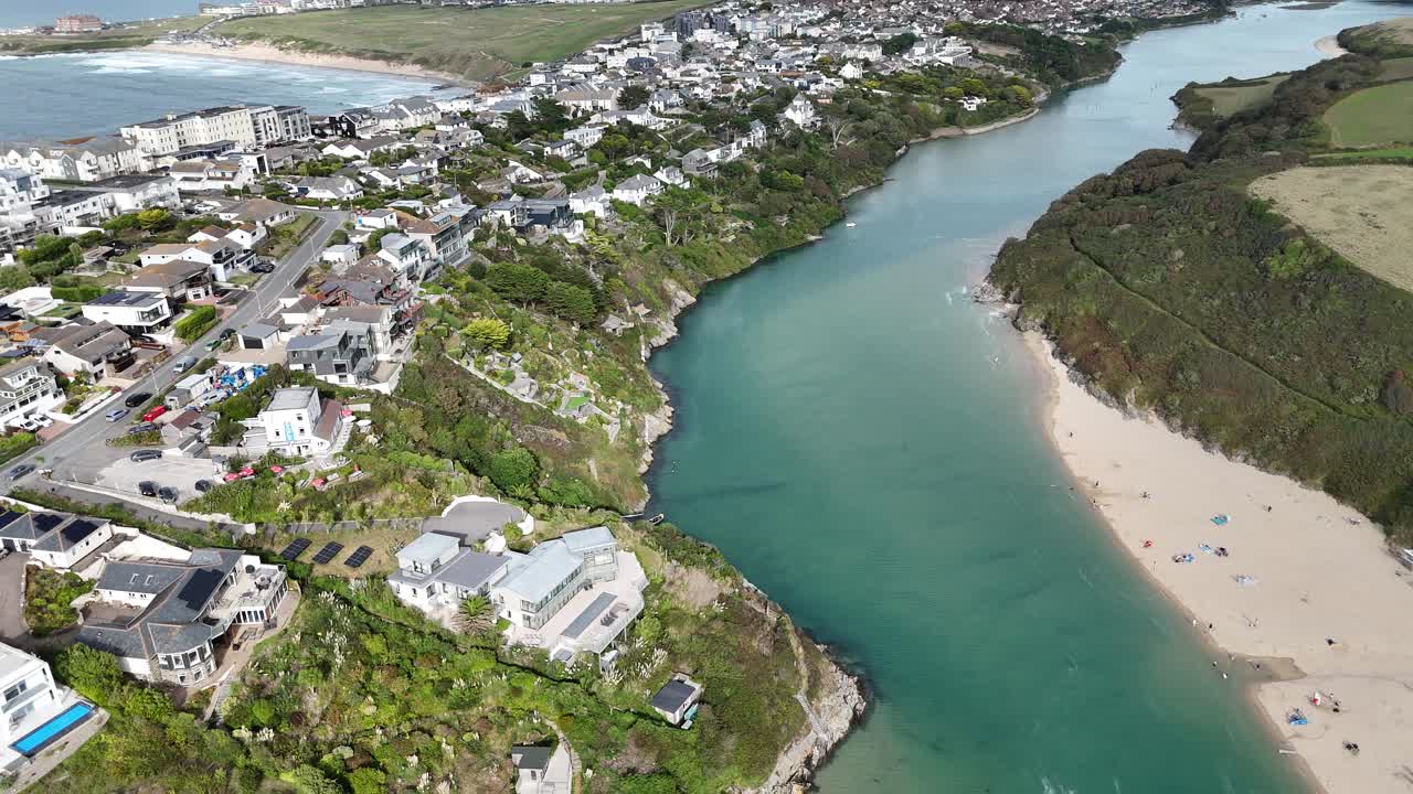 Ripresa aerea con drone del fiume Hamble in Hampshire, Inghilterra, che mostra acqua blu calma serpeggiante tra case costiere, vegetazione verde e rive sabbiose sotto la luce chiara del giorno