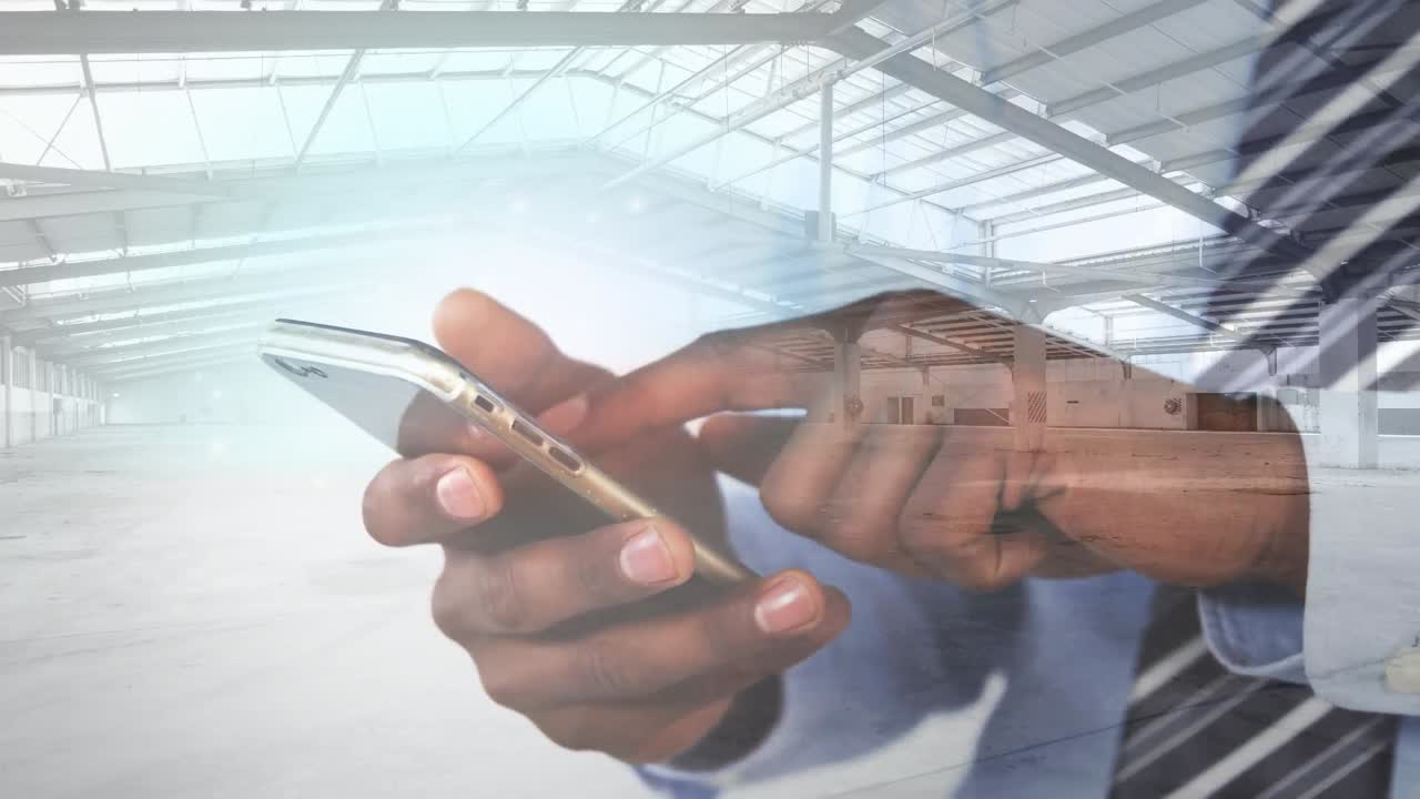 Animation of warehouse over african american man using smartphone