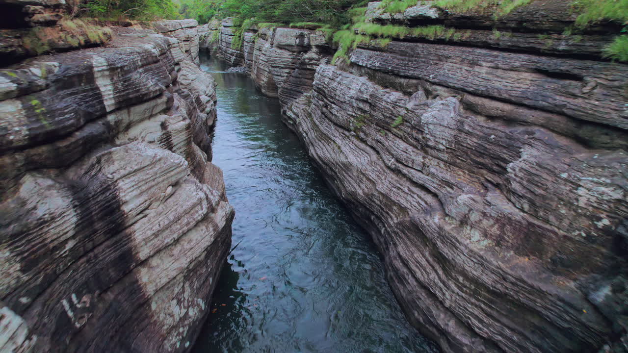 el agua corriendo a través del cañón rocoso en capas de cajones de chame, panamá, la exuberante vegetación por encima