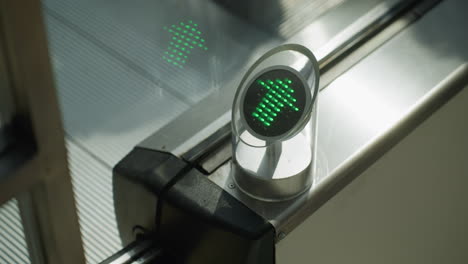 a very close-up view capturing the detail of escalator steps and a person going down. the focus is on the mechanical parts and the green directional light