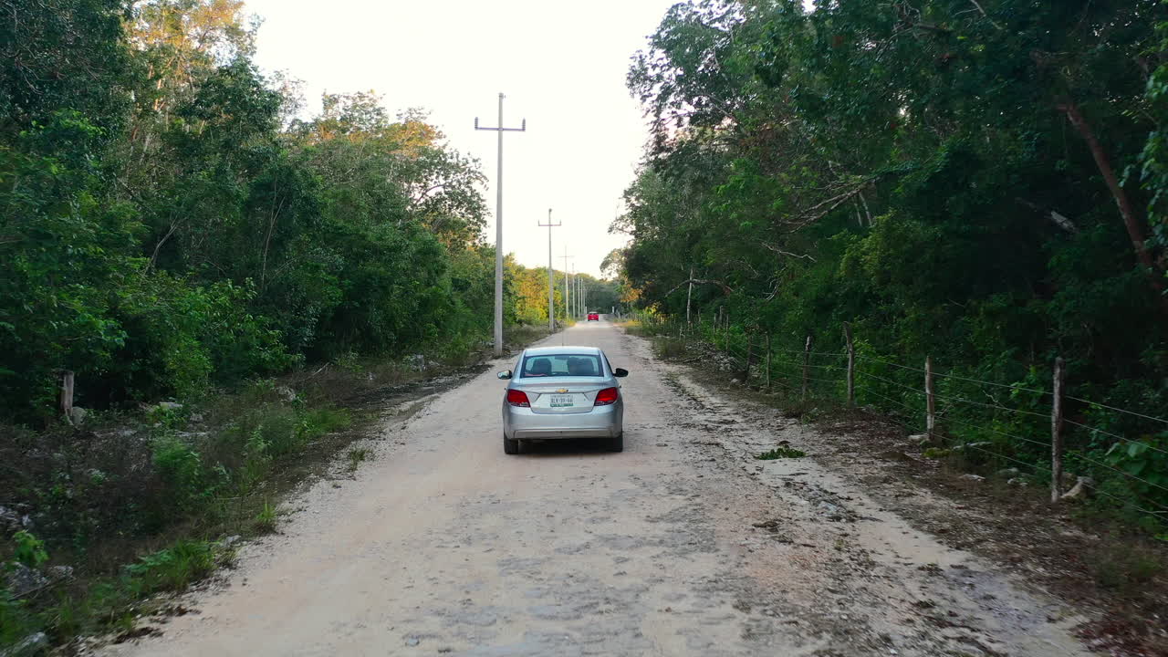 toma de seguimiento aéreo de la conducción de automóviles en la carretera en coba quintana roo méxico al atardecer