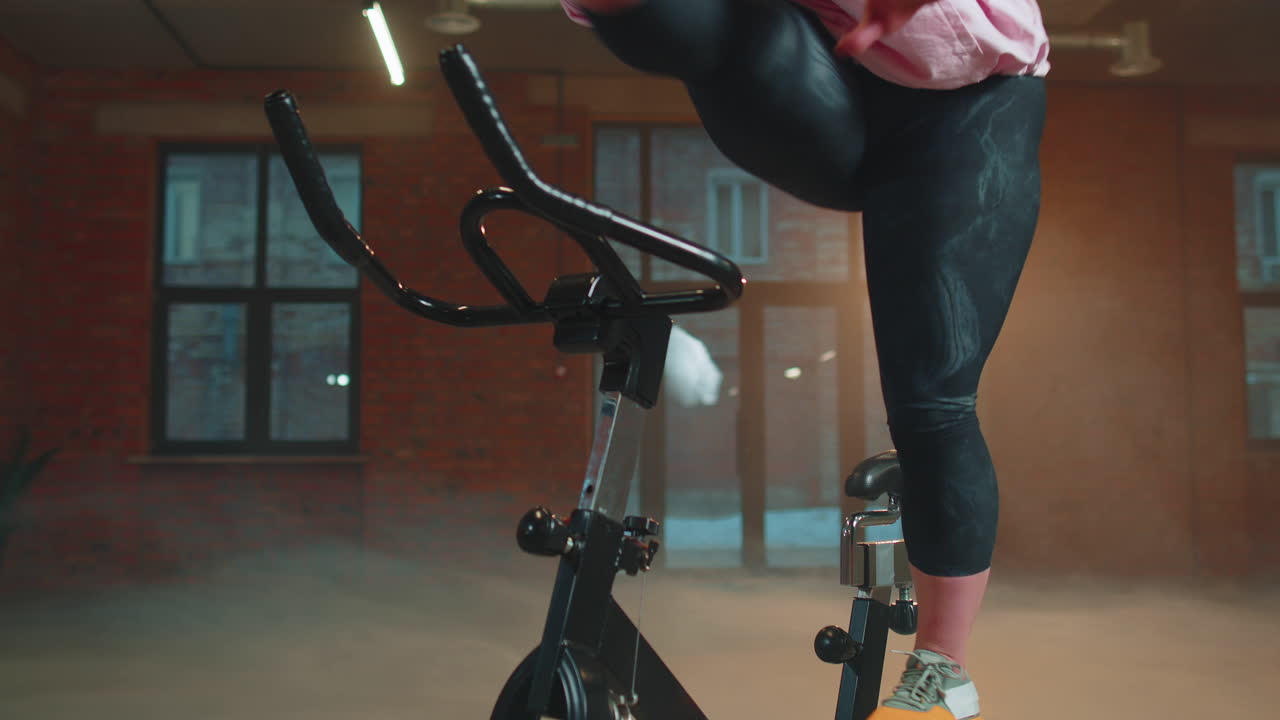 여성은 시 ⁇ 레이터, 사이클 트레이닝에서 유산소 지구력 훈련 운동 심장 루틴을 수행합니다.
