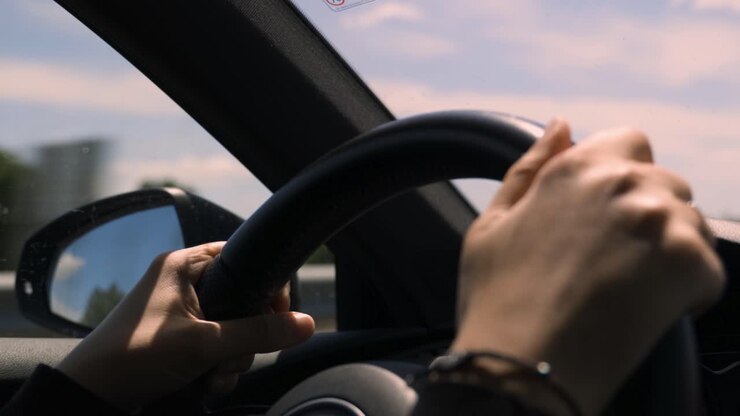 Mains nerveuses au volant d'une voiture, gros plan sur le volant et les mains d'une femme