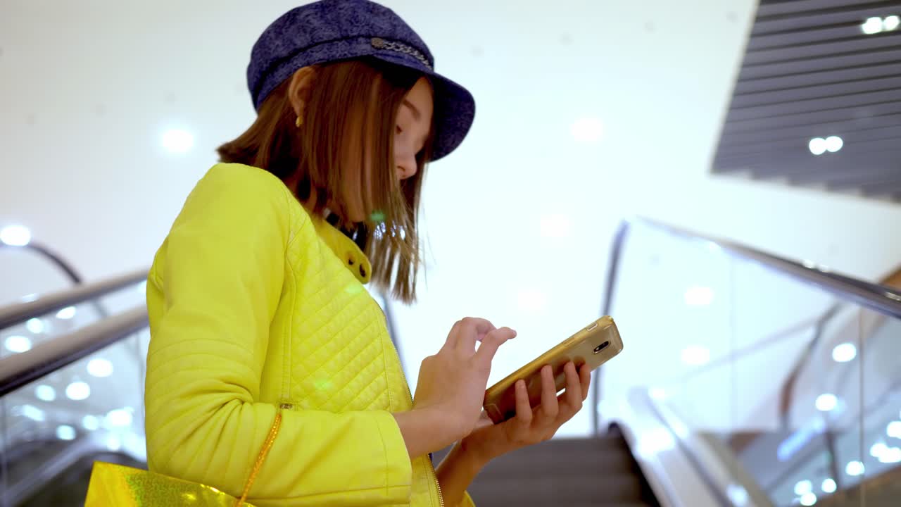 Teenage Girl Using Phone on Escalator in Shopping Mall
