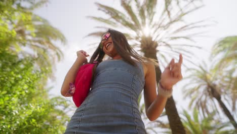 happy young woman dancing outdoors under sunny palm trees