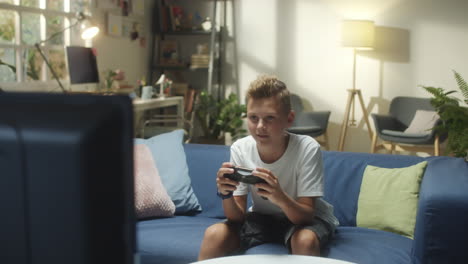 young boy playing video games and celebrating victory on the couch