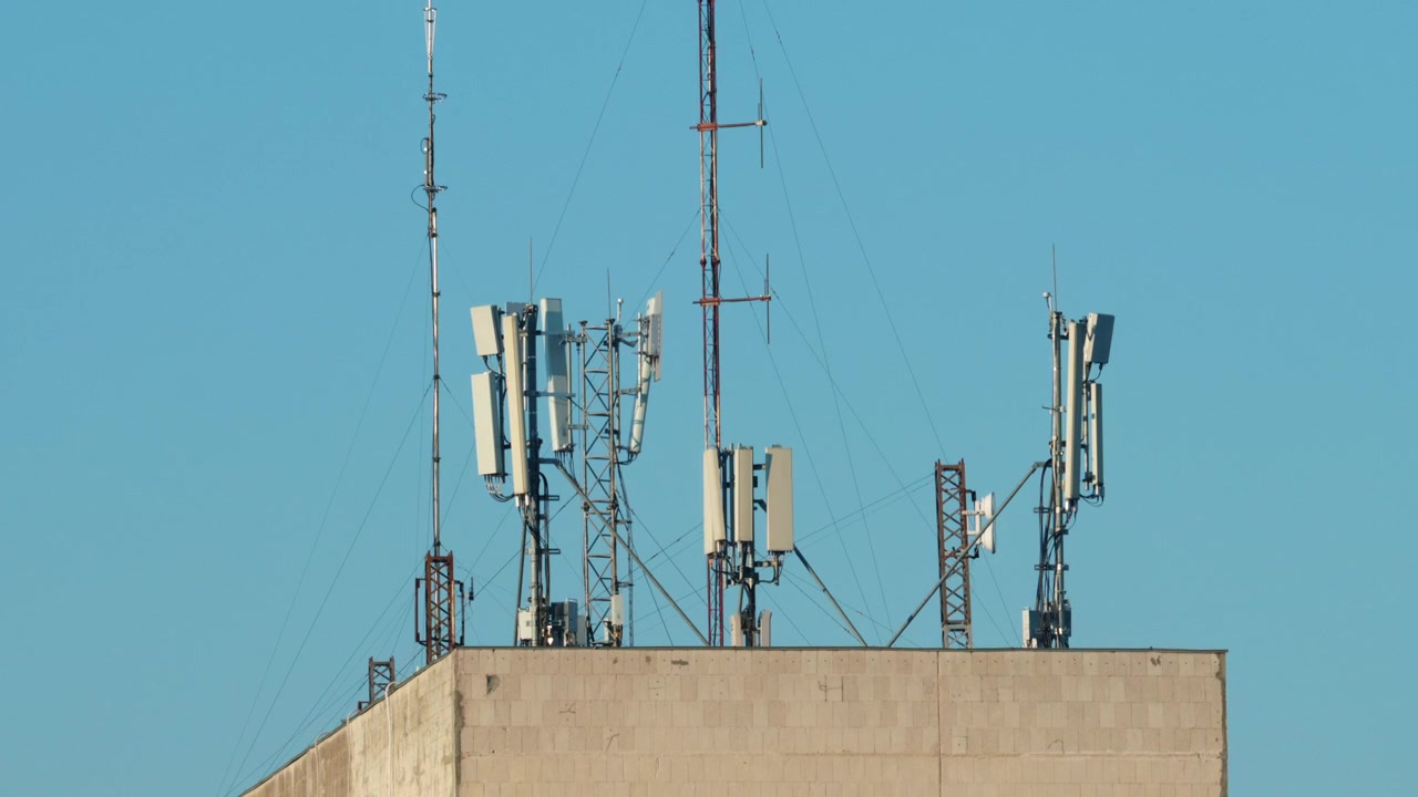 Close up of a telecommunications antenna mounted on a metal tower structure against a clear blue sky