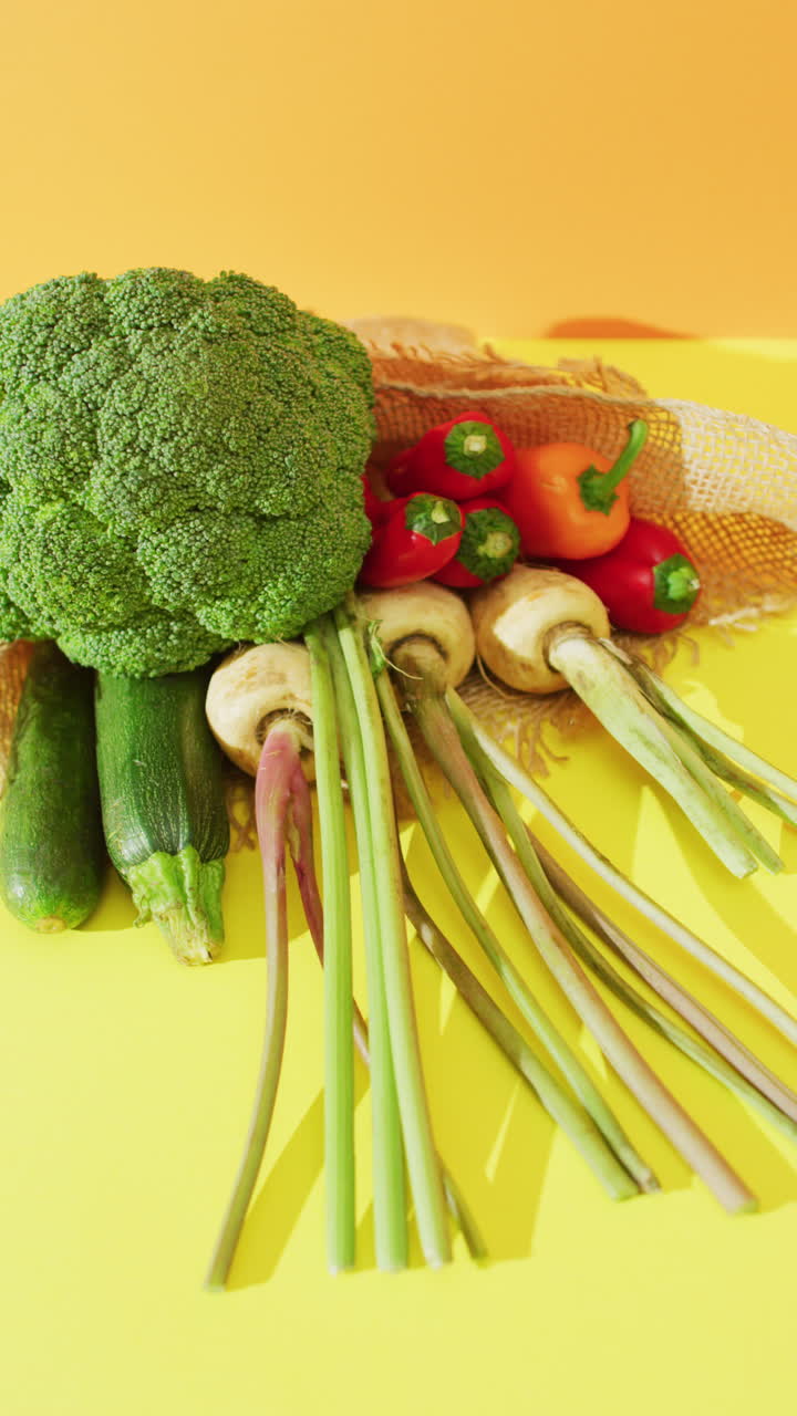 노란색 배경에 브로콜리와 고추를 가진 신선한 채소의 수직 비디오