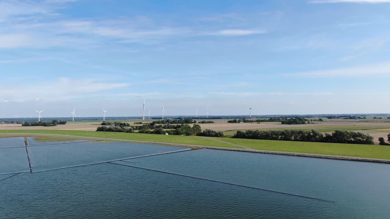 Zoom out wide shot of North Sea,natural landscape with grazing sheeps and turbine farm in background.