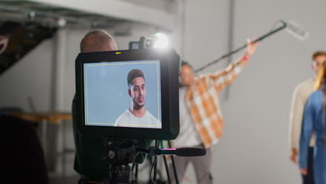 actors shooting movie or video in studio with film crew and female director watching monitor in foreground 1