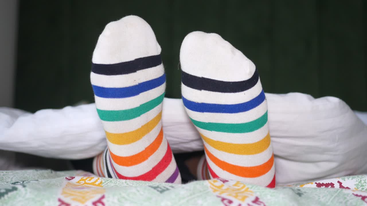 calcetines a rayas de colores en los pies en la cama