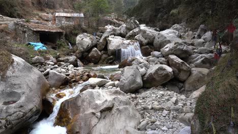 un pequeño río que fluye en las estribaciones del himalaya con pequeñas cabañas de piedra a su lado