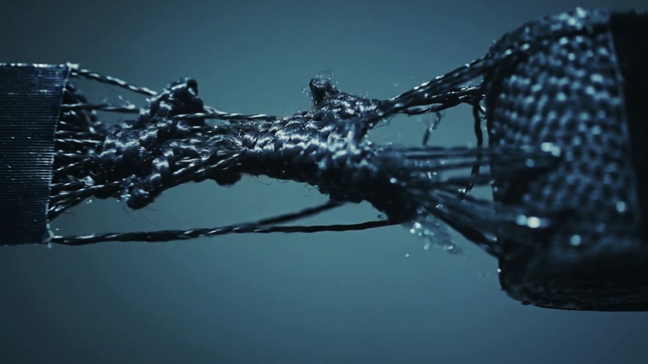 Pulling black woven strap and smooth strip in studio, revealing frayed yarns and debris