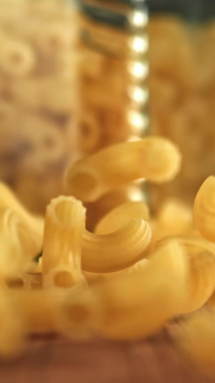 Maccheroni secchi che cadono al rallentatore su una superficie di legno