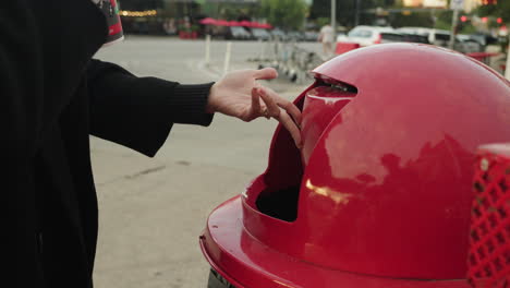 Woman-throws-away-single-use-disposable-drink-container-with-plastic-straw-in-trash-bin-on-street