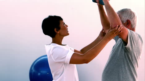 Elderly-man-lifting-hand-weights-with-physiotherapist