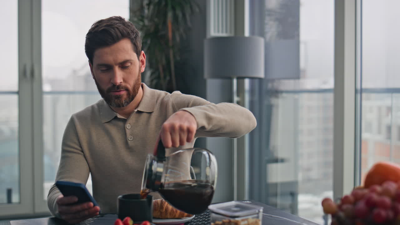 un hombre de negocios ocupado vertiendo una taza de café en un primer plano panorámico de la cocina.