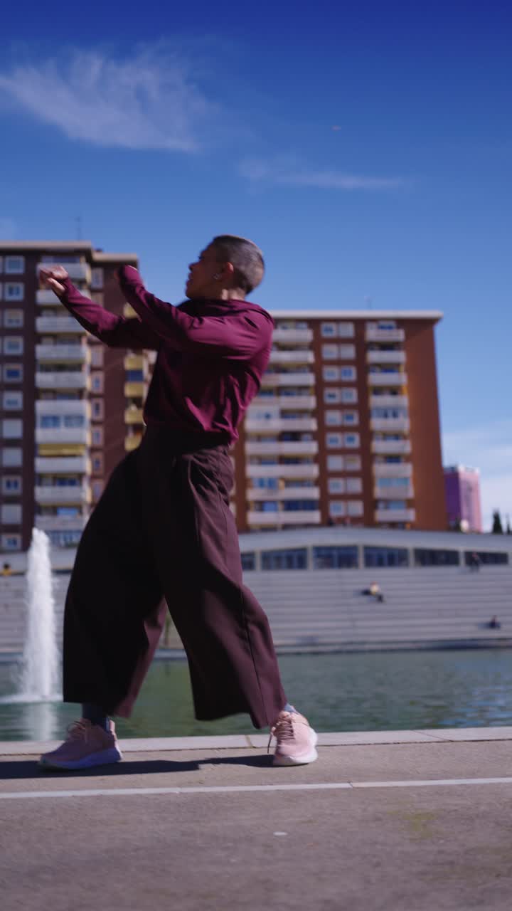 Donna energica che esegue movimenti di danza contemporanea in un parco urbano