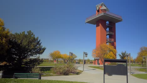 a man walks to a park bench beside a watchtower at a city park