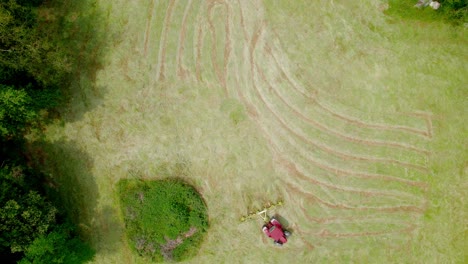 High-angle-view-of-red-lawn-mower-moving-through-green-field-cutting-grass