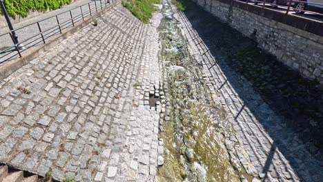 cobblestone path beside lake with parked cars