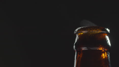 close up of condensation droplets on neck of bottle of cold beer or soft drink with water vapour after opening 2