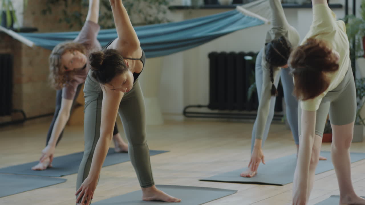 Women Practicing Triangle Pose on Yoga Class