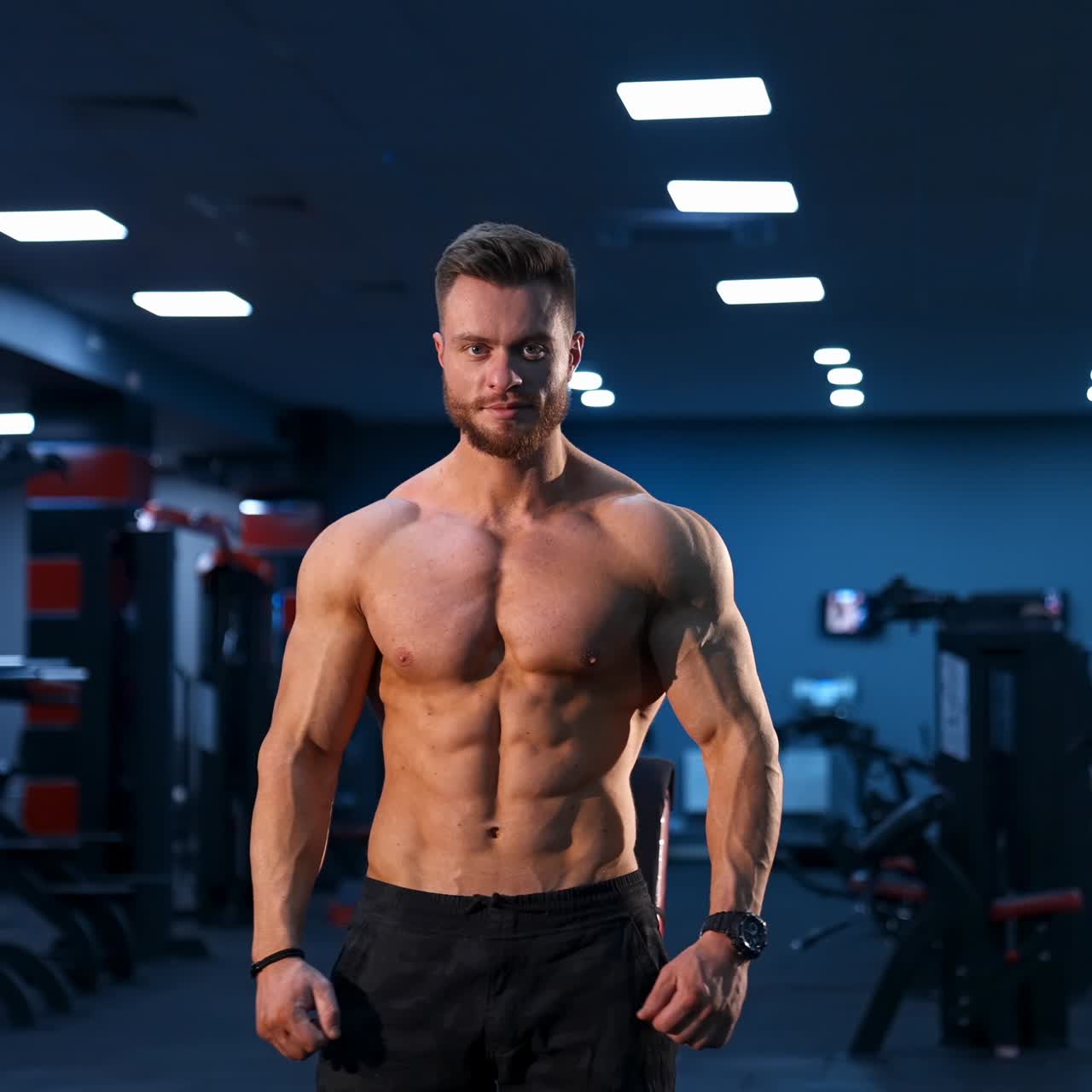 Circle view on bodybuilder without shirt in gym. Man with strong hands and big muscles. Slow motion
