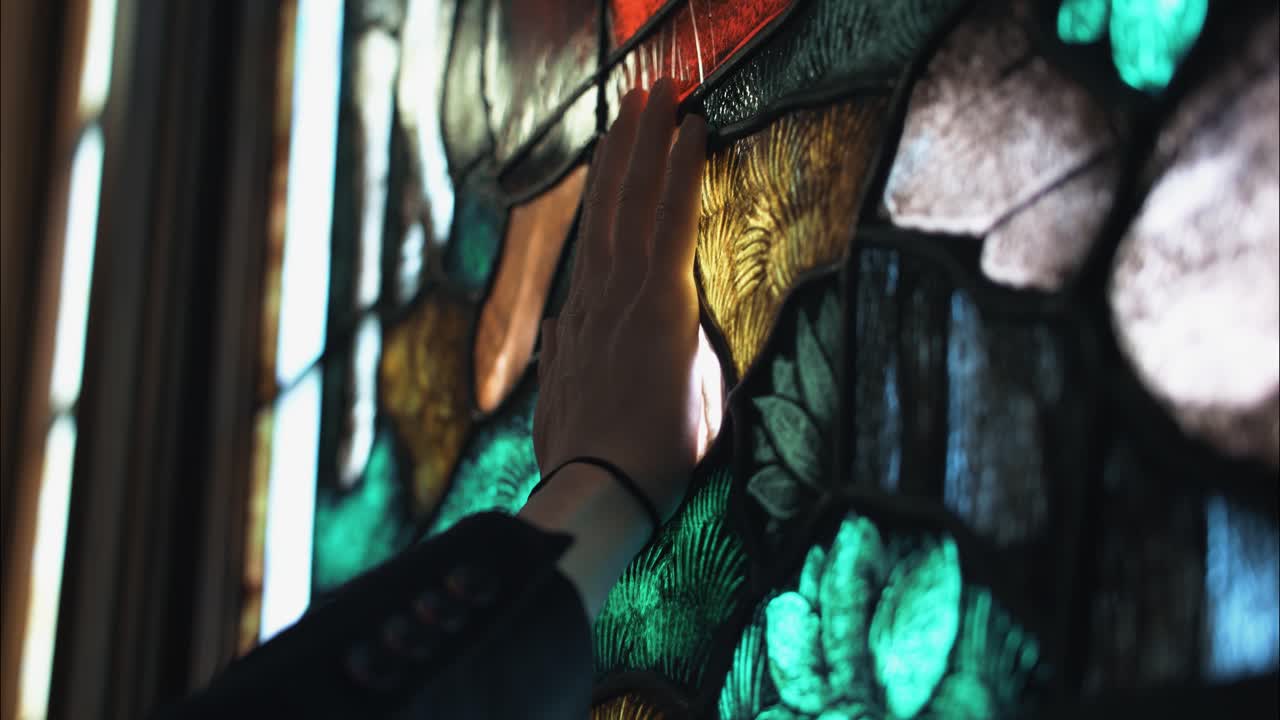A man's hand touches the feet of Jesus on stained glass church window in moment of worship, prayer and spiritual reflection