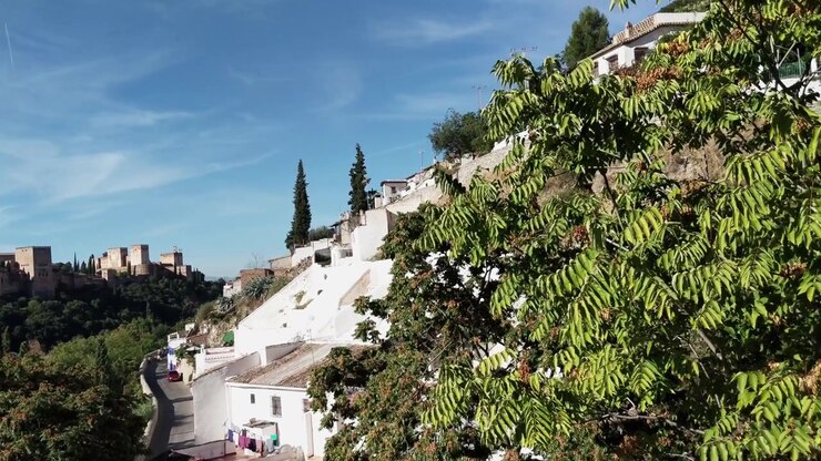 Câmera em movimento panorâmico lento e inclinação para cima, revelando a beleza do famoso bairro espanhol de Granada, o Sacromonte