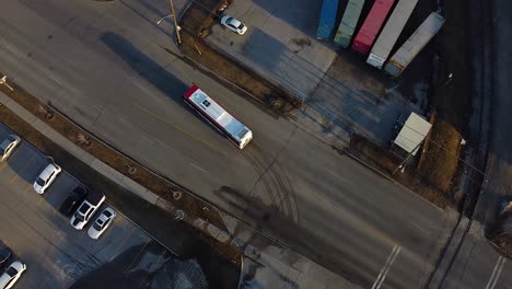 ttc public transit bus leaves large operations, maintenance and storage facility and drives on road from top down