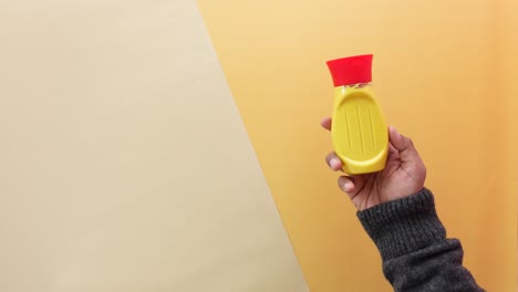 hand holding a yellow mustard bottle