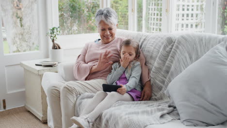 little girl using smartphone with grandmother having video chat waving at family sharing vacation weekend with granny chatting on mobile phone relaxing at home with granddaughter 4k