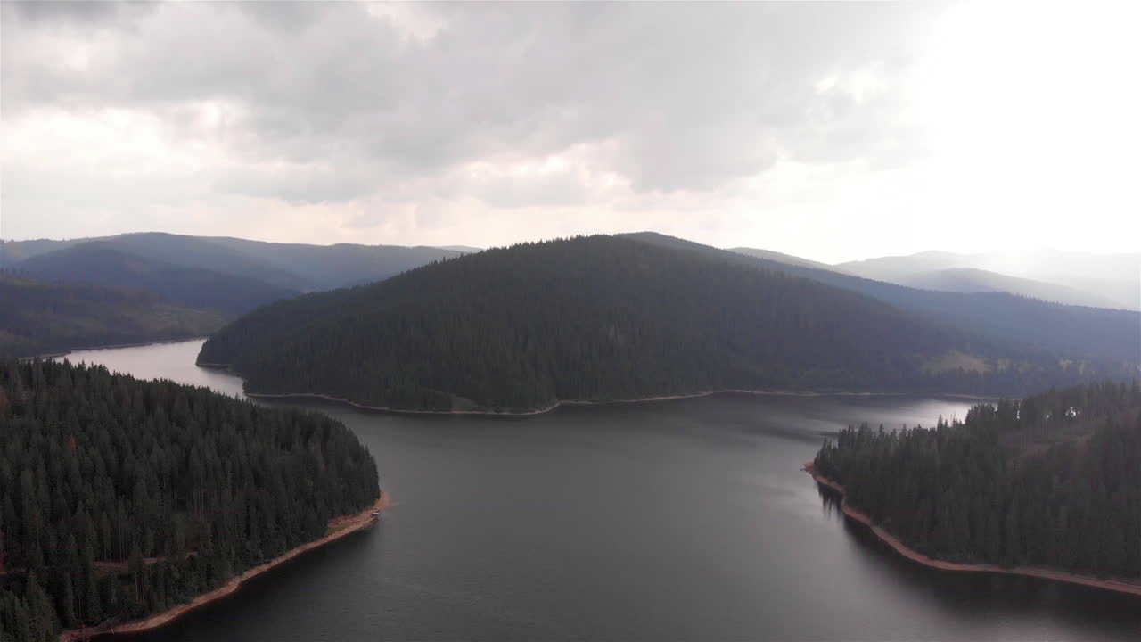 Filmato aereo di un grande lago e montagne circondati da una foresta
