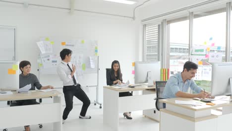 crazy happy businessman dancing in corporate.handsome young businessman doing victory dance about successful achievement and throwing paper documents. happy male at modern office