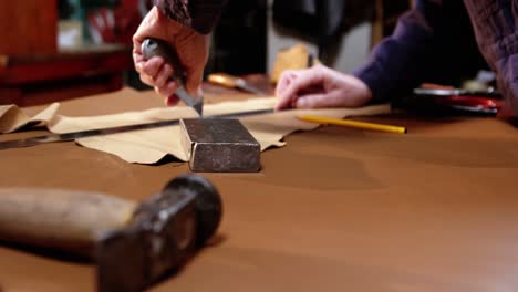 shoemaker cutting a piece of leather