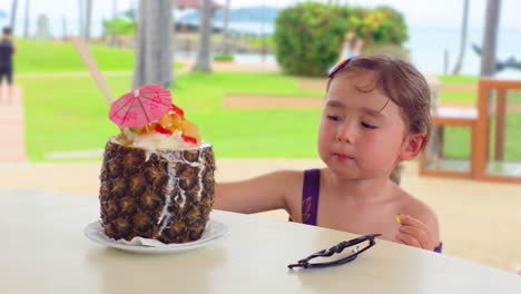 adorable little girl eating exotic ice cream with jellies at the tropical beach